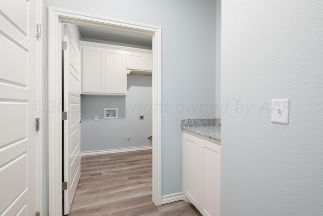 laundry room featuring hookup for a washing machine, light hardwood / wood-style flooring, and cabinets