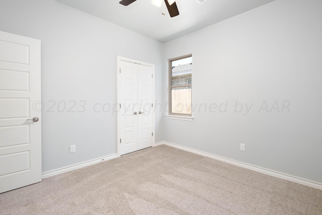 unfurnished bedroom featuring light carpet, a closet, and ceiling fan