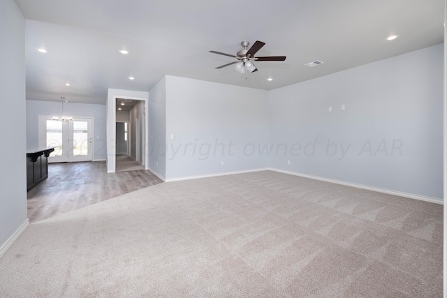 spare room featuring carpet floors and ceiling fan with notable chandelier