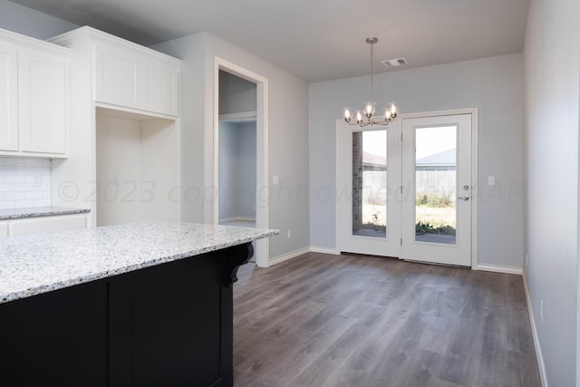 kitchen with decorative light fixtures, white cabinets, light stone counters, dark wood-type flooring, and an inviting chandelier