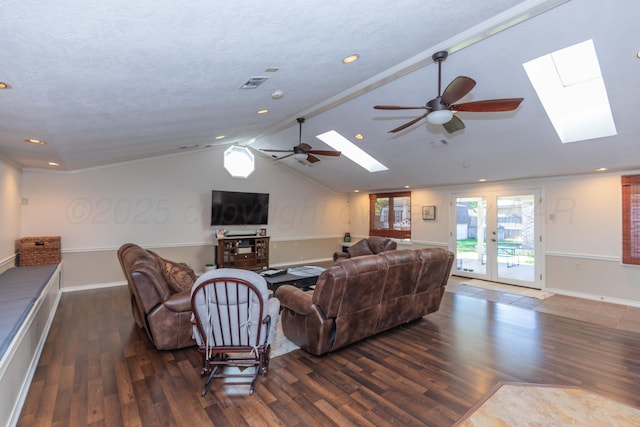 living area featuring a skylight, ceiling fan, wood finished floors, lofted ceiling, and baseboards