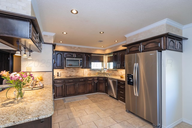kitchen with appliances with stainless steel finishes, light stone counters, a sink, dark brown cabinets, and decorative backsplash