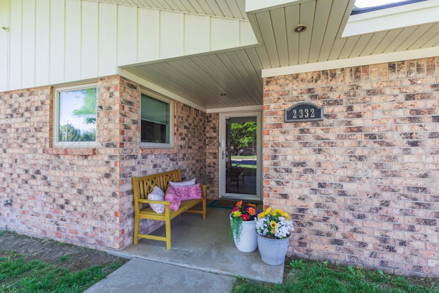 doorway to property with brick siding and board and batten siding