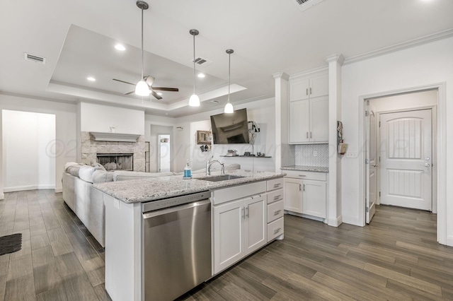 kitchen featuring dishwasher, a ceiling fan, a sink, and a tray ceiling