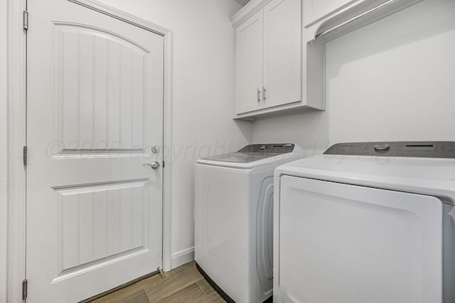 clothes washing area featuring separate washer and dryer, wood finished floors, and cabinet space