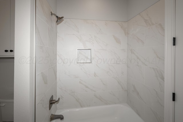 bathroom featuring tiled shower / bath and toilet