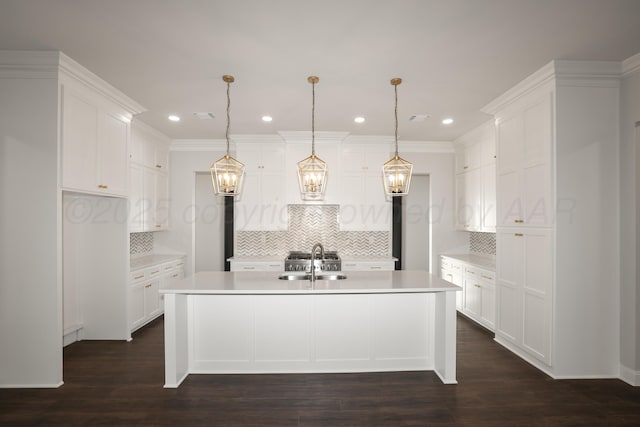 kitchen with white cabinetry, sink, pendant lighting, and a kitchen island with sink