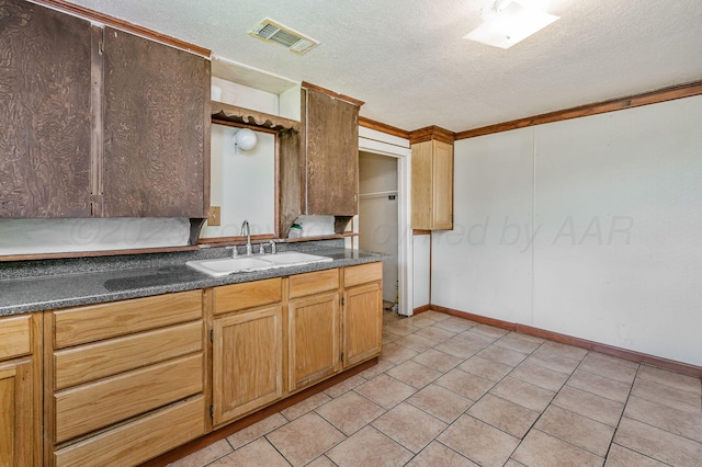 102 S Sumner St, Pampa, TX 79065 - kitchen with a sink, a textured ceiling, dark countertops, light tile patterned floors, and baseboards