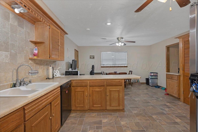 kitchen featuring a ceiling fan, a sink, black dishwasher, a peninsula, and light countertops