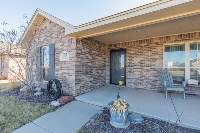 property entrance with a patio and brick siding