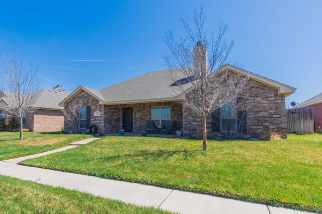 ranch-style house featuring a chimney, a front lawn, and brick siding