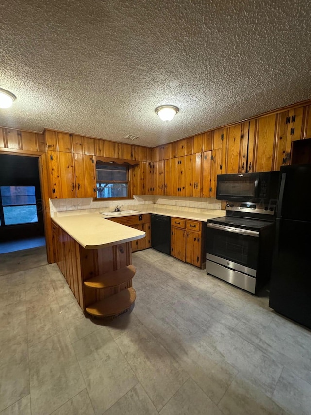 kitchen with kitchen peninsula, black appliances, and a textured ceiling