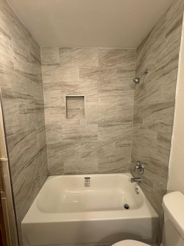 bathroom featuring tiled shower / bath combo and toilet