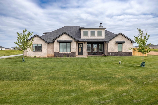 view of front of house with fence, a front lawn, roof with shingles, a porch, and brick siding