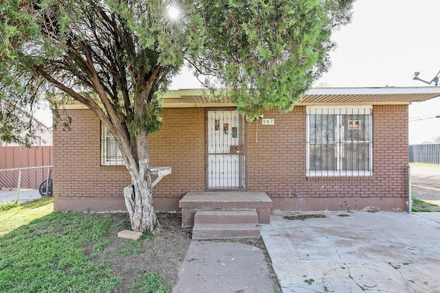 entrance to property featuring brick siding and fence