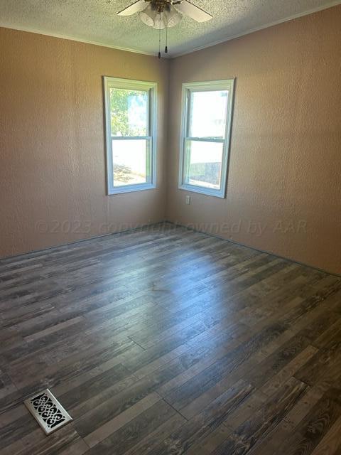 spare room with ceiling fan, dark wood-type flooring, and a textured ceiling