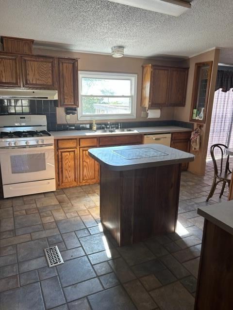 kitchen featuring white range with gas cooktop, sink, a kitchen island, and a textured ceiling