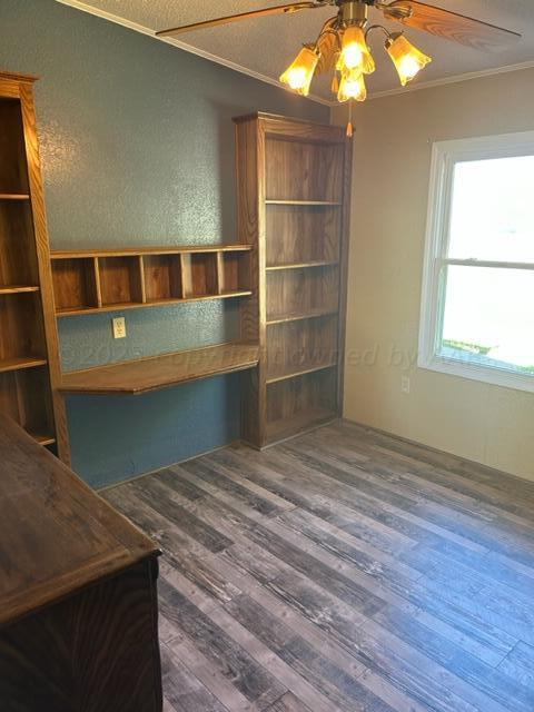 unfurnished office featuring dark hardwood / wood-style floors, ceiling fan, ornamental molding, and a textured ceiling