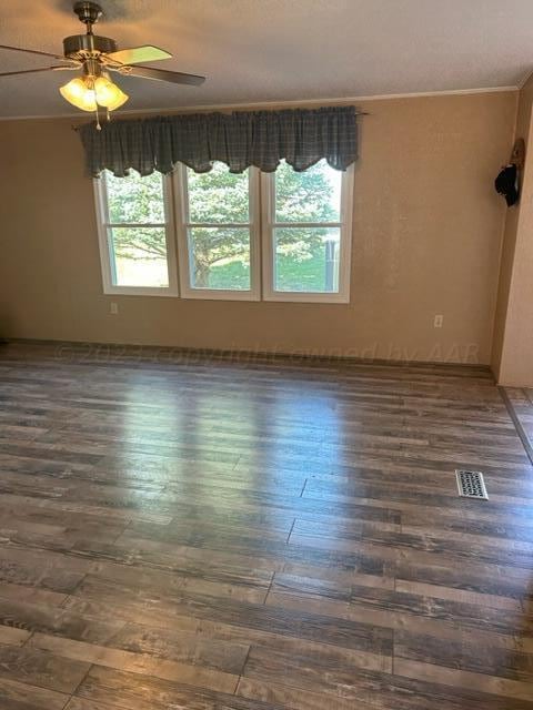 unfurnished room with dark hardwood / wood-style floors, a wealth of natural light, ornamental molding, and ceiling fan