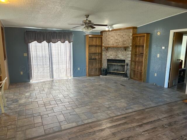 unfurnished living room with a brick fireplace, a textured ceiling, vaulted ceiling, ceiling fan, and wood-type flooring