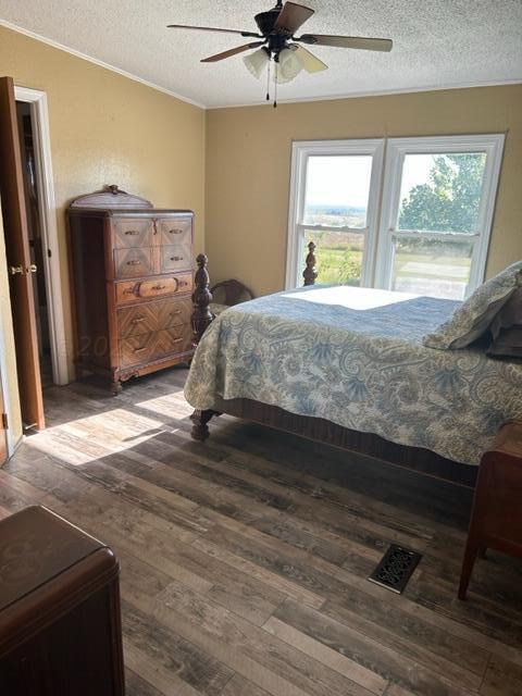 bedroom featuring a textured ceiling, dark hardwood / wood-style floors, and ceiling fan