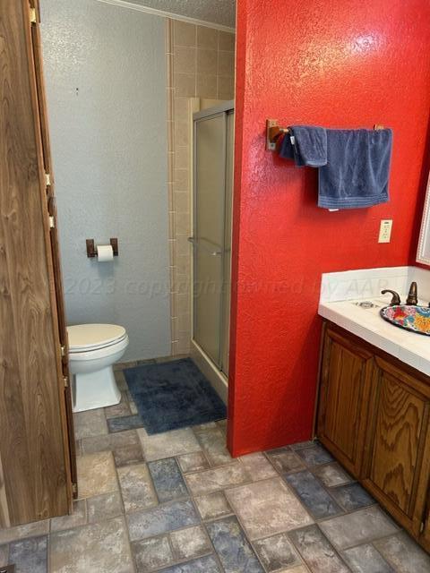 bathroom featuring vanity, toilet, and a shower with door