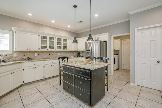 7826 Tarrytown Ave, Amarillo, TX 79121 - kitchen featuring washer / clothes dryer, white cabinetry, a breakfast bar area, and tasteful backsplash