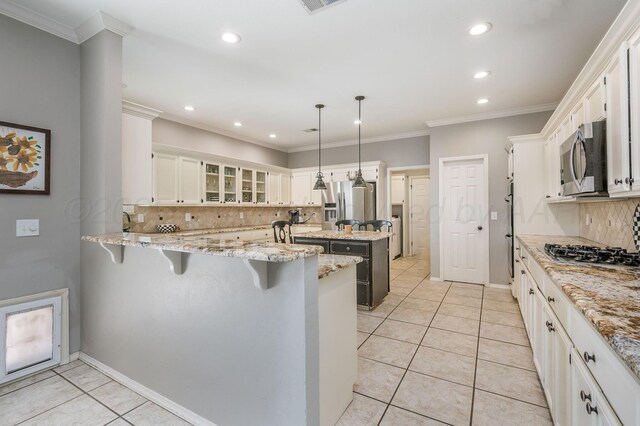 7826 Tarrytown Ave, Amarillo, TX 79121 - kitchen with light stone countertops, appliances with stainless steel finishes, a breakfast bar area, a peninsula, and tasteful backsplash