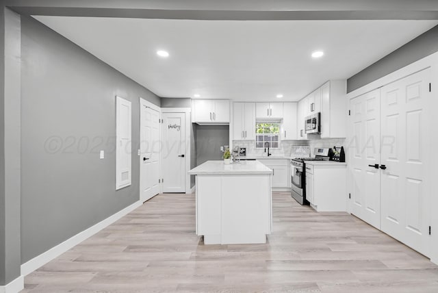 1108 N Taylor St, Amarillo, TX 79107 - kitchen featuring stainless steel appliances, light wood-style flooring, tasteful backsplash, white cabinets, and light countertops