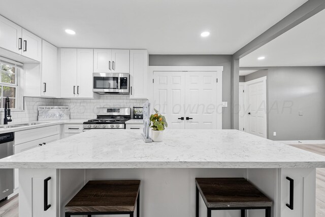 1108 N Taylor St, Amarillo, TX 79107 - kitchen featuring appliances with stainless steel finishes, backsplash, a kitchen bar, light stone countertops, and recessed lighting