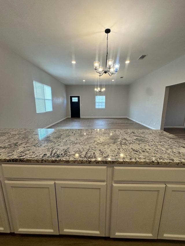 kitchen with light stone countertops, hanging light fixtures, a healthy amount of sunlight, and white cabinets