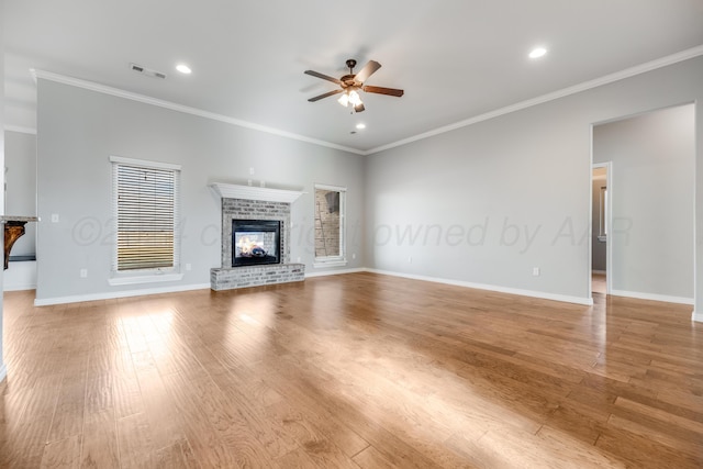 unfurnished living room with crown molding, ceiling fan, a brick fireplace, and light hardwood / wood-style flooring