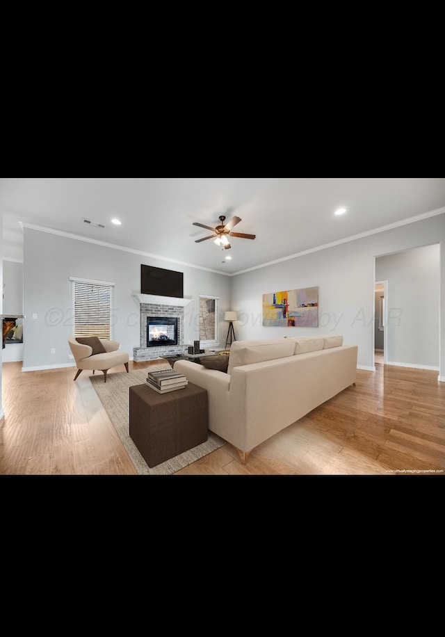 living room featuring ornamental molding, a tile fireplace, and light hardwood / wood-style floors
