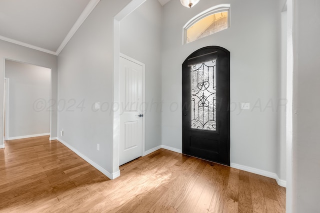foyer entrance featuring a high ceiling, crown molding, and light wood-type flooring