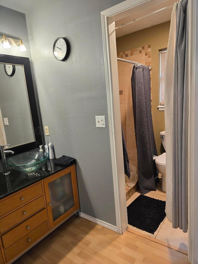 bathroom featuring walk in shower, wood-type flooring, toilet, and vanity