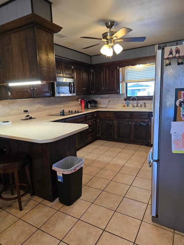 kitchen with appliances with stainless steel finishes, sink, backsplash, light tile patterned floors, and kitchen peninsula