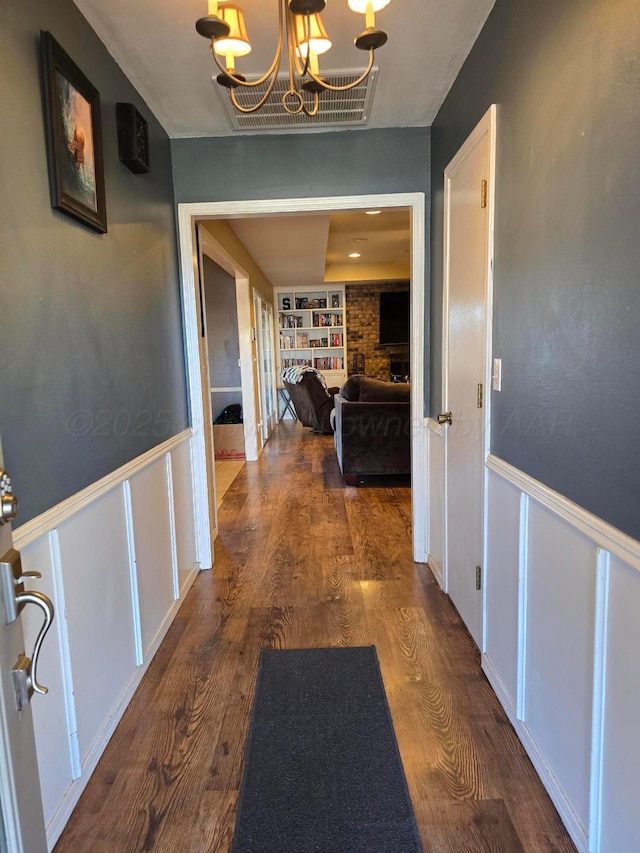 hall with dark wood-type flooring and a chandelier