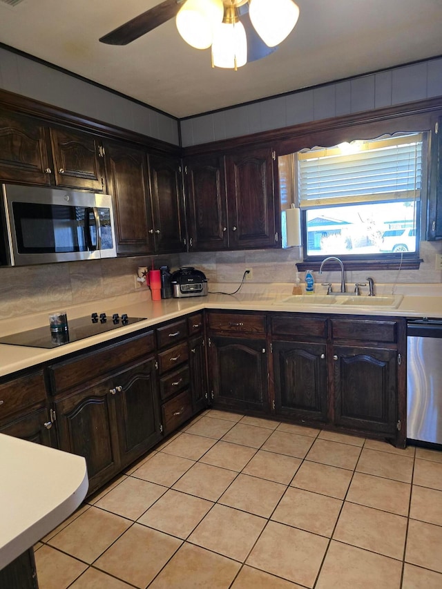 kitchen featuring dark brown cabinetry, sink, light tile patterned floors, appliances with stainless steel finishes, and backsplash