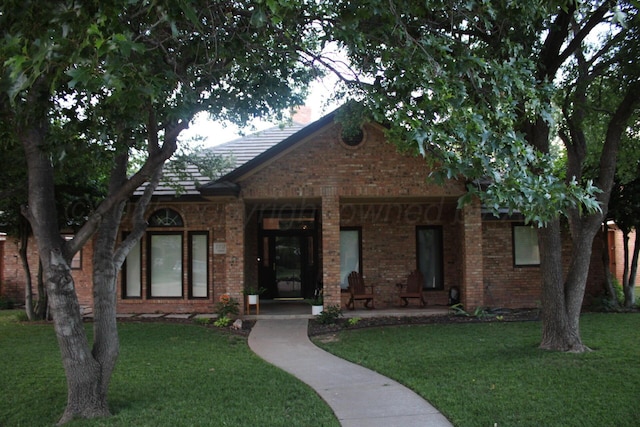 7717 Tripp Ave, Amarillo, TX 79121 - tudor house with covered porch, a front lawn, and brick siding