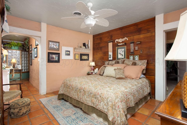 803 N Locust St, Wildorado, TX 79098 - tiled bedroom with arched walkways, wooden walls, and a ceiling fan