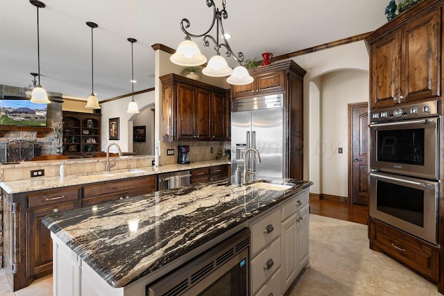 2501 Mackenzie Trl, Amarillo, TX 79124 - kitchen featuring a sink, built in appliances, arched walkways, and a kitchen island with sink