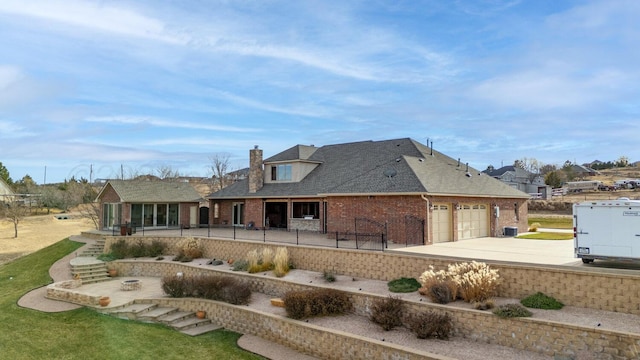 2501 Mackenzie Trl, Amarillo, TX 79124 - back of house with brick siding, concrete driveway, a chimney, a patio area, and an attached garage