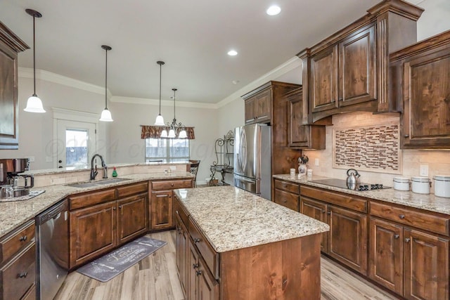 kitchen featuring stainless steel appliances, sink, decorative light fixtures, crown molding, and a center island