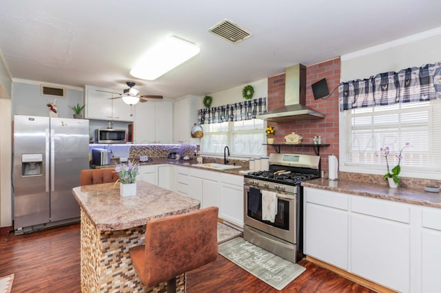 2041 S Travis St, Amarillo, TX 79109 - kitchen with stainless steel appliances, wall chimney range hood, dark wood-style flooring, ceiling fan, and white cabinets
