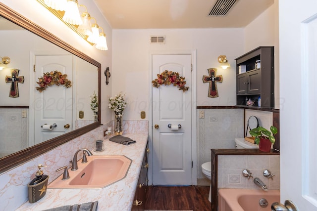 2041 S Travis St, Amarillo, TX 79109 - full bathroom with tile walls, a bath, vanity, wood finished floors, and a wainscoted wall