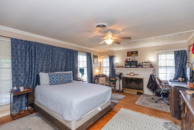 2041 S Travis St, Amarillo, TX 79109 - bedroom featuring multiple windows, crown molding, light wood-style floors, a brick fireplace, and a ceiling fan