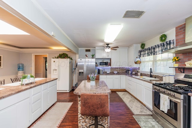 2041 S Travis St, Amarillo, TX 79109 - kitchen featuring appliances with stainless steel finishes, wall chimney exhaust hood, white cabinets, light stone counters, and ceiling fan