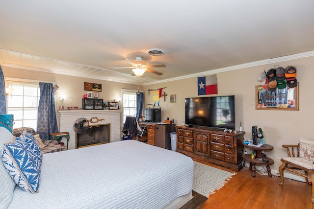 2041 S Travis St, Amarillo, TX 79109 - bedroom featuring multiple windows, wood finished floors, crown molding, a brick fireplace, and ceiling fan