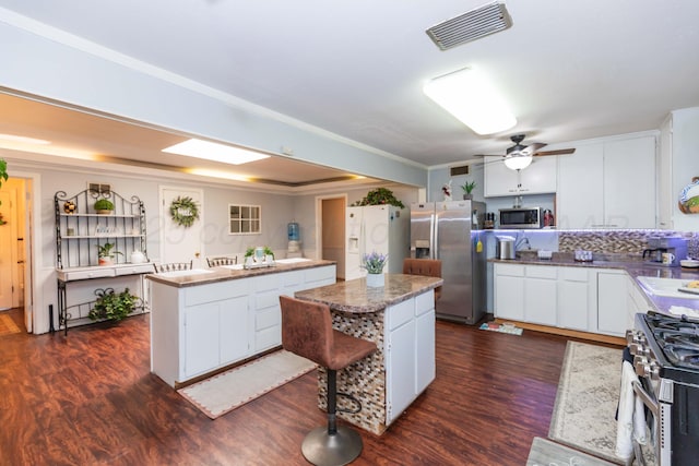 2041 S Travis St, Amarillo, TX 79109 - kitchen featuring a center island, appliances with stainless steel finishes, dark wood-style floors, white cabinets, and a ceiling fan