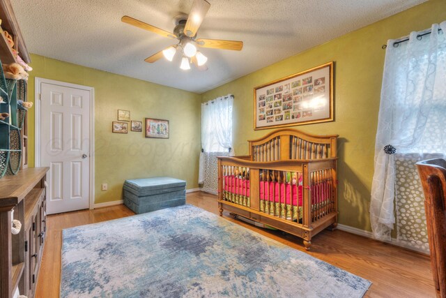 5200 Kingswood Cir, Amarillo, TX 79109 - bedroom featuring wood finished floors, a textured ceiling, ceiling fan, and a crib